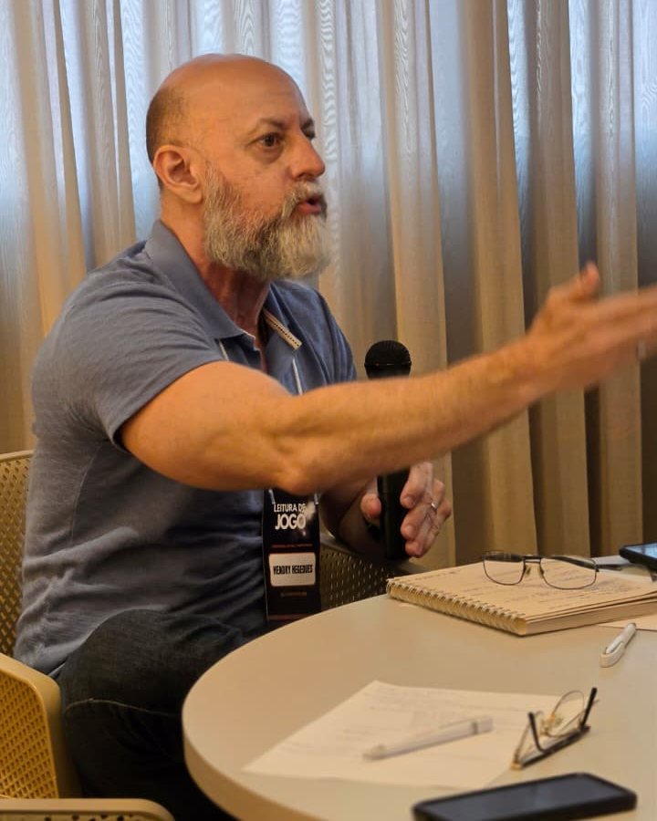 Hendry Hegedues, ao microfone, conduzindo uma discussão em um encontro de trabalho